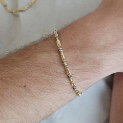 Photo of worn Tubular bracelet with round striped partridge eye in yellow gold alternating with 2 white eyelets